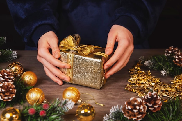 Girl decorates Christmas gifts Top view on wooden table background Celebrating Christmas and New Years