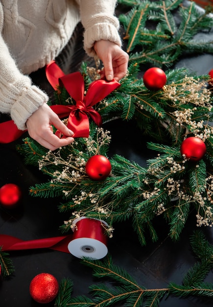 女の子は自宅のテーブルに自分でクリスマスリースを飾ります