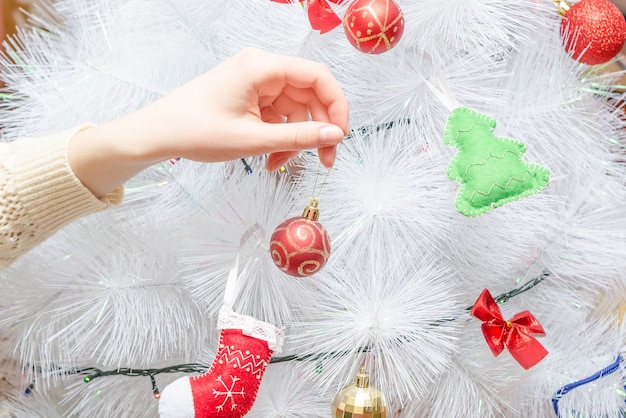 사진 소녀는 빨간 공 크리 에이 티브 화이트 크리스마스 트리를 장식합니다. 연말 연시 및 크리스마스 휴가 준비