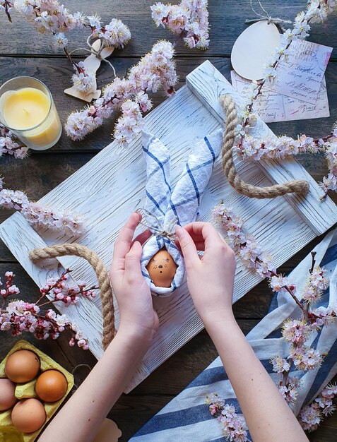 A girl decorates an Easter egg with a cloth napkin