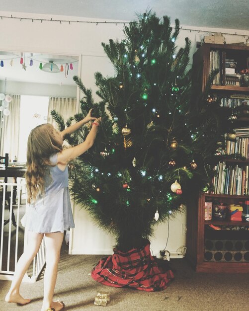 Photo girl decorating christmas tree at home