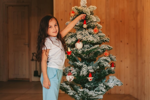 Una ragazza che decora un albero di natale a casa