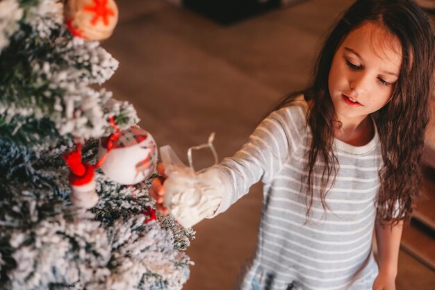 家でクリスマスツリーを飾る女の子