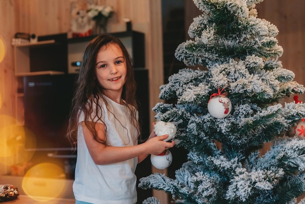 a girl decorating a Christmas tree at home