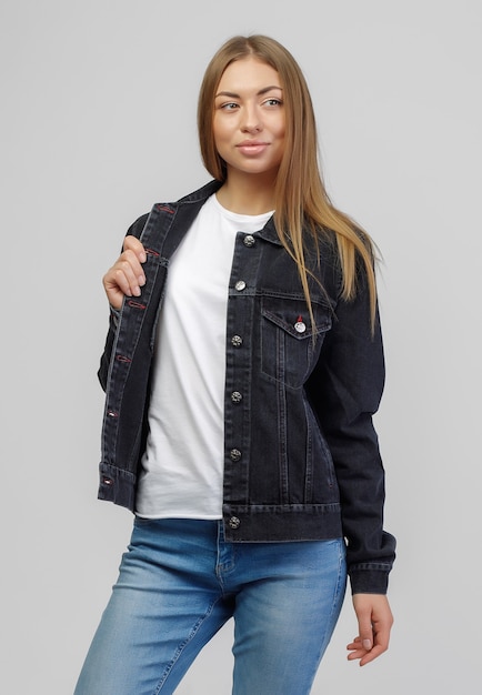 Girl in a denim black jacket and blue denim pants on a white background