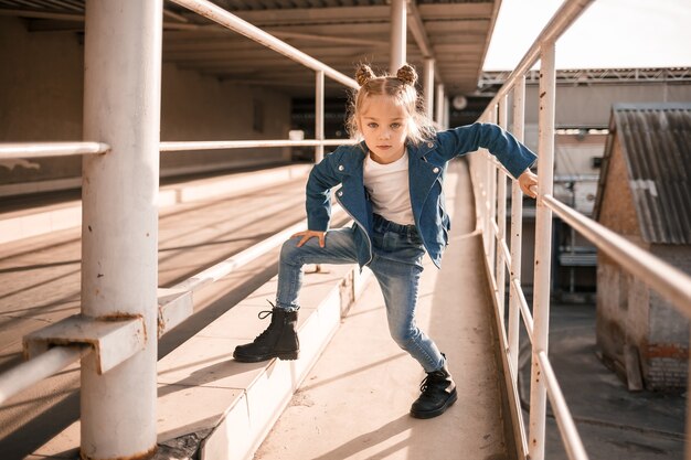Девушка в джинсовой одежде танцует хип-хоп на парковке