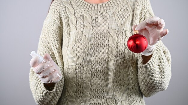 女の子はクリスマスのおもちゃを消毒します。検疫でクリスマスを祝う。高品質の写真