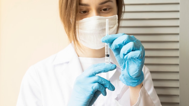 Girl doctor holds a syringe in her hand with a medicine against coronavirus