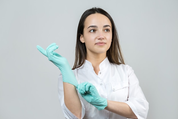 A girl doctor in latex gloves and a white coat is preparing for the procedures.