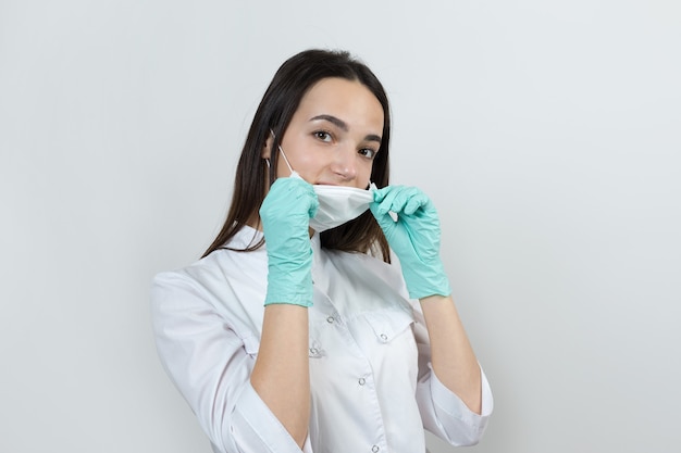 Девушка-врач в латексных перчатках и белом халате готовится к процедурам.
