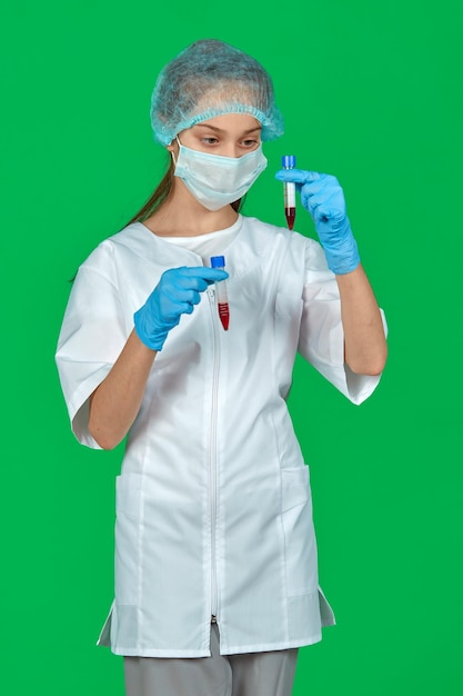 A girl doctor with test tubes in her hands stands on a green background