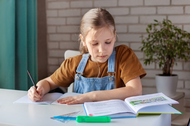 A girl does homework with a book at home.