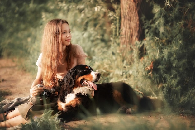 A girl and a dog are sitting on the banks of the river