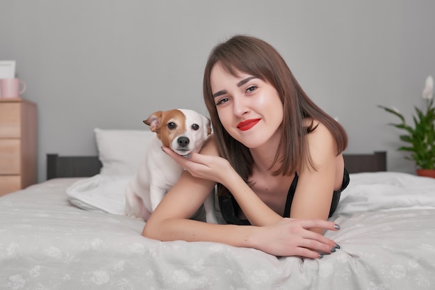 Girl and dog in bed. beautiful woman in pajamas, enjoys morning weekend. cozy morning