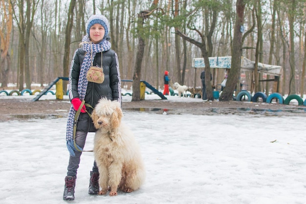 A girl and a dog royal poodle in winter