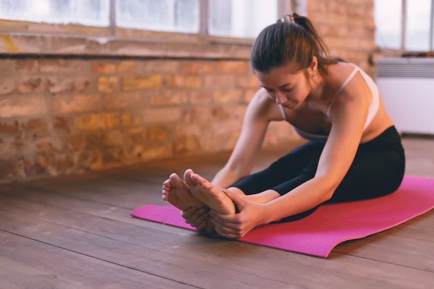 Foto ragazza che fa un asana che si piega in avanti con le mani verso le sue gambe