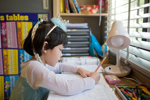 宿題をしている女の子が学校に戻って紙の教育の概念を書いている子供