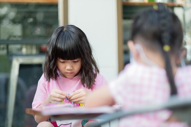 宿題をしている女の子が学校に戻って紙の教育の概念を書いている