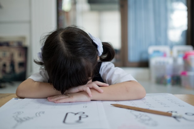 写真 宿題をしている女の子が学校に戻って紙の教育の概念を書いている子供