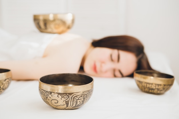 Girl doing massage therapy singing bowls in the Spa