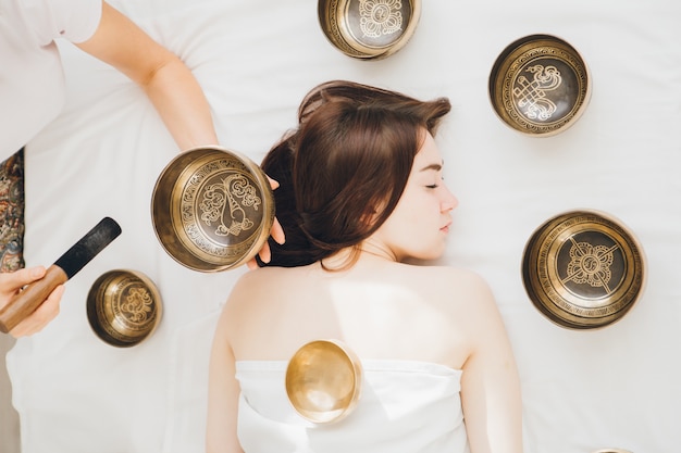 Girl doing massage therapy singing bowls in the Spa