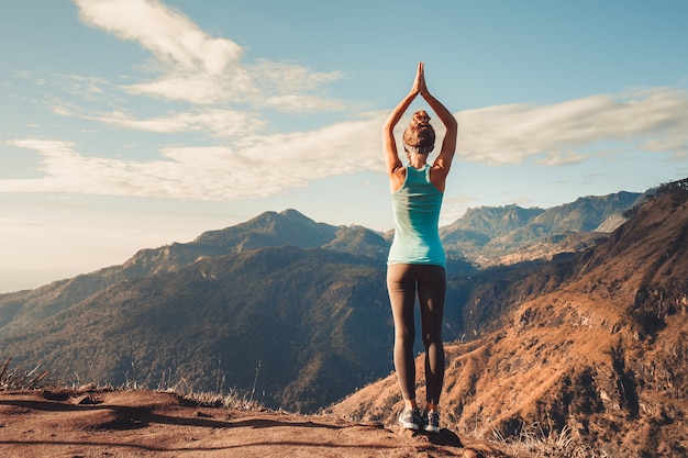 Girl doing a stand on balance at the top of the mountain