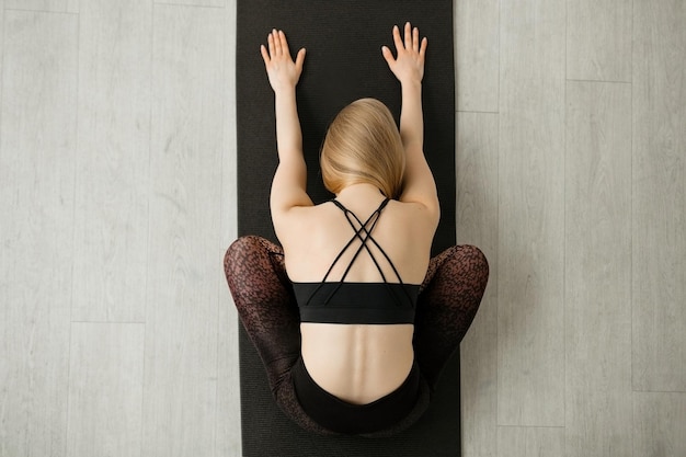 Ragazza che fa stretching sulla vista dall'alto della stuoia di yoga