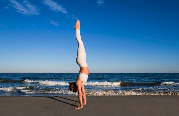 Girl doing yoga on the beach shore