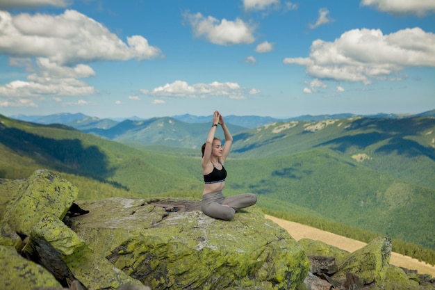 Girl doing yoga exercise lotus pose at the top of the mountain