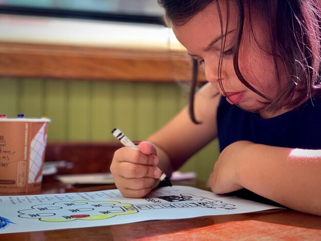 Foto ragazza che disegna su carta sul tavolo a casa