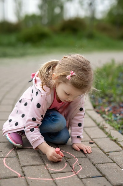 Girl drawing with chalk on the sidewalk