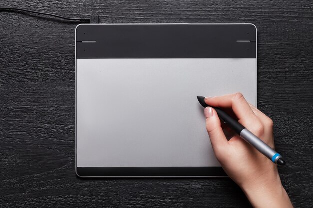 Girl draws on the black graphic tablet