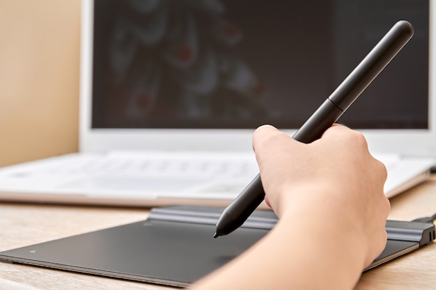 Girl draws on a graphics tablet with pen