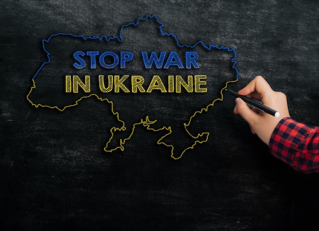 La ragazza disegna una mappa dell'ucraina con il testo stop war in ukraine sulla lavagna