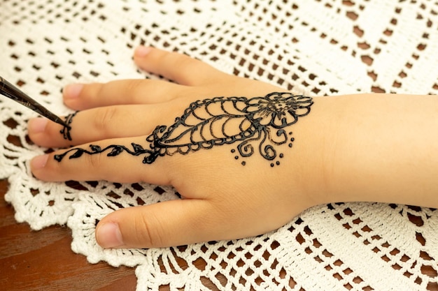 The girl draws patterns with henna on the child's hand