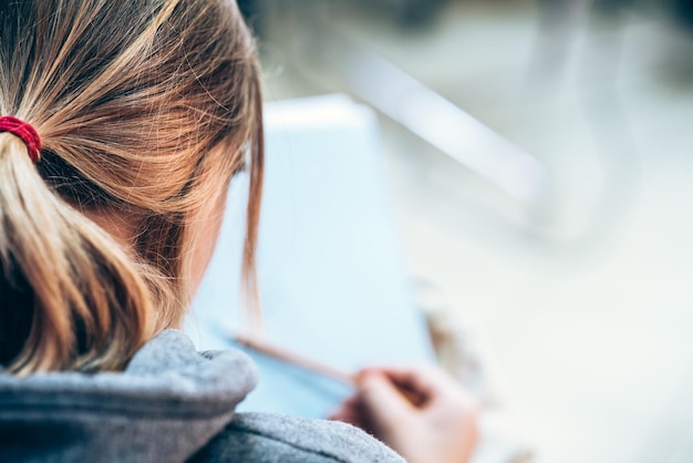 Girl draws a pencil in the albumview from the back closeup