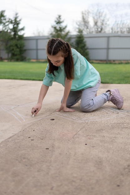 Girl draws with colorful crayons on pavement Children39s drawings with chalk on wall Creative kid Joy of childhood