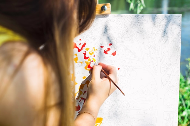 The girl draws a yellow paint brush on the canvas with numbers with the brush