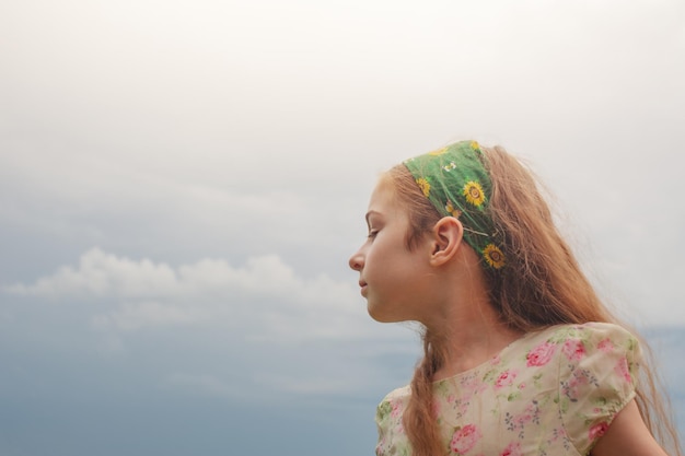 Девушка в платье на фоне неба Портрет девочки-подростка с длинными волосами