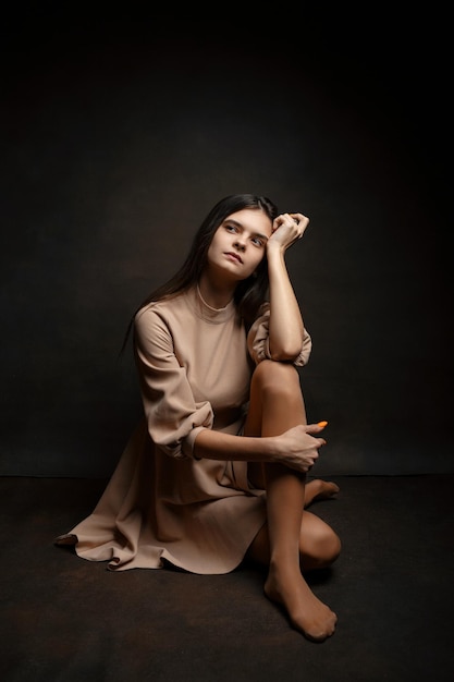 Photo a girl in a dress on a brown background