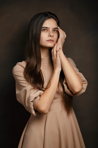 Photo a girl in a dress on a brown background