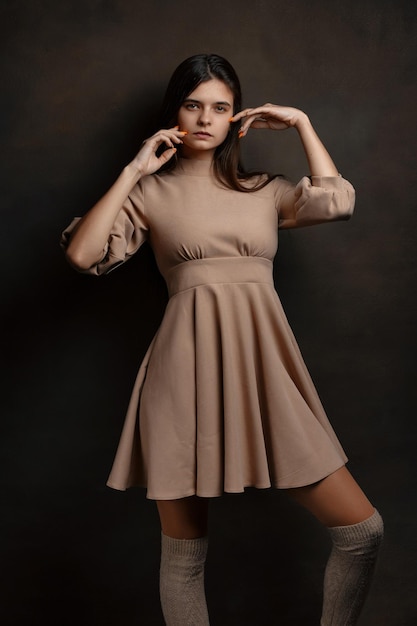 Photo a girl in a dress on a brown background