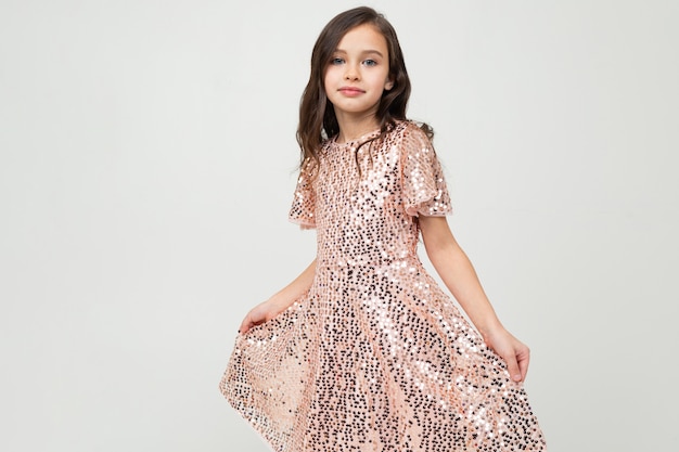 Girl in a dress for the holiday posing on a white studio wall