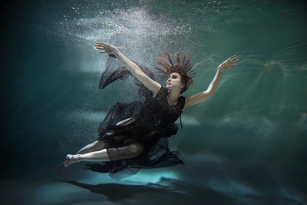 Girl in a dress levitates underwater