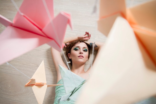 Girl in dress looking at paper of birds. Origami cranes.