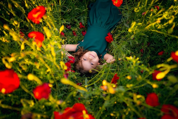 Ragazza in vestito e cappello di paglia all'aperto al campo di papaveri