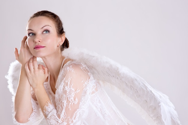 A girl dressed as an angel on a light background