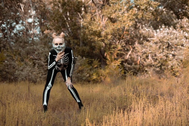 A girl dressed as a skeleton wearing a mask with rhinestones looks scary into the camera Halloween