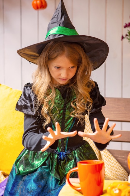 girl dressed as a witch with a pumpkin in halloween portrait of a witch