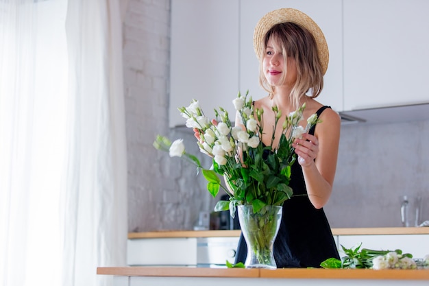 Ragazza vestita in un abito nero vicino bouquet di rose bianche in un vaso